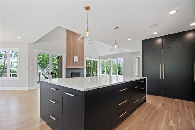 2616 W 112th St, Leawood, KS 66211 - kitchen with dark cabinetry, lofted ceiling, light countertops, light wood-type flooring, and hanging light fixtures
