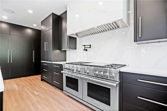 2616 W 112th St, Leawood, KS 66211 - kitchen with range with two ovens, custom range hood, dark cabinets, light countertops, and recessed lighting