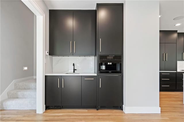 2616 W 112th St, Leawood, KS 66211 - indoor wet bar featuring light wood finished floors, stairway, and tasteful backsplash