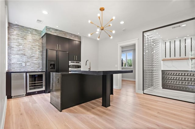 2616 W 112th St, Leawood, KS 66211 - kitchen with wine cooler, stainless steel appliances, light wood finished floors, a chandelier, and recessed lighting
