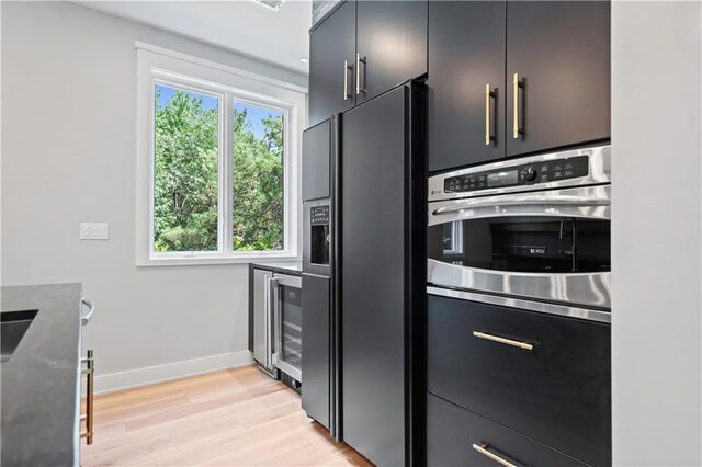 2616 W 112th St, Leawood, KS 66211 - kitchen featuring black fridge with ice dispenser, wine cooler, light wood-type flooring, and dark cabinets