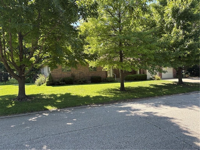 105 N Hayes St, Garnett, KS 66032 - view of property hidden behind natural elements with an attached garage, a front lawn, brick siding, and concrete driveway