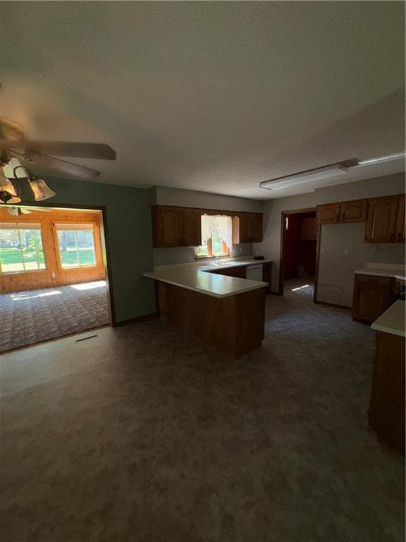 105 N Hayes St, Garnett, KS 66032 - kitchen with a peninsula, healthy amount of natural light, a textured ceiling, light countertops, and brown cabinetry