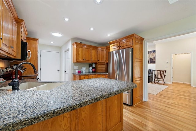 1311 SE Eastridge Cir, Blue Springs, MO 64014 - kitchen with freestanding refrigerator, a peninsula, light wood-style flooring, brown cabinetry, and dark stone countertops