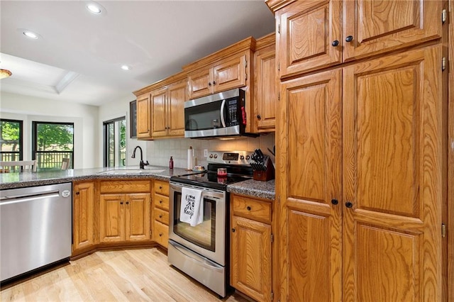 1311 SE Eastridge Cir, Blue Springs, MO 64014 - kitchen with appliances with stainless steel finishes, light wood finished floors, tasteful backsplash, recessed lighting, and brown cabinets