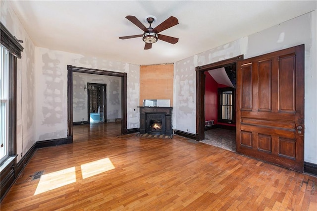 118 Spruce St, Leavenworth, KS 66048 - unfurnished living room featuring ceiling fan, light wood-style floors, and a lit fireplace