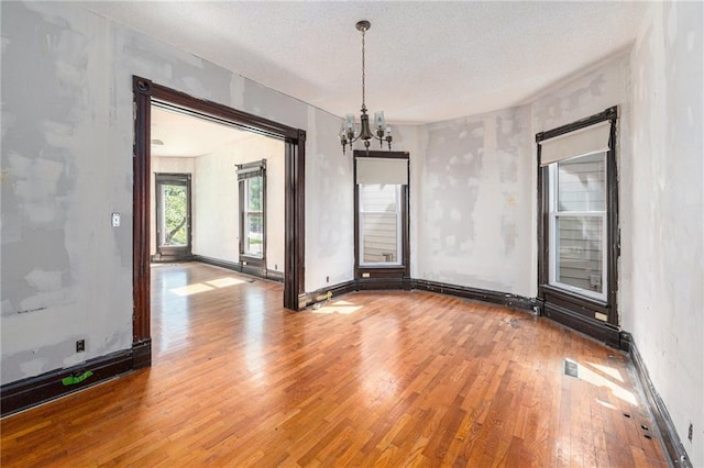 118 Spruce St, Leavenworth, KS 66048 - spare room with wood finished floors, a chandelier, and a textured ceiling