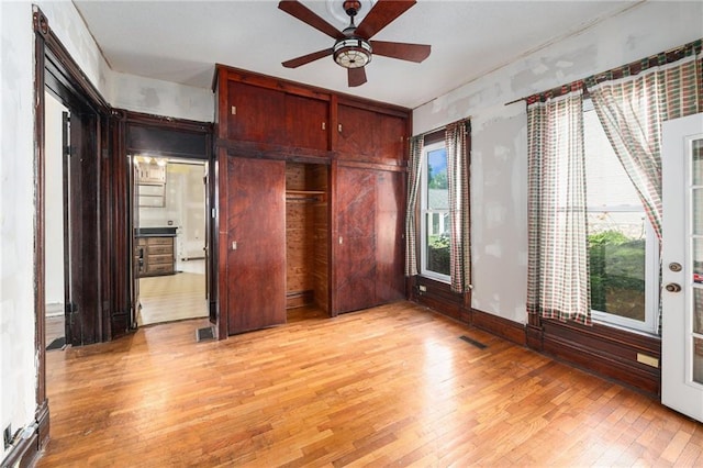 118 Spruce St, Leavenworth, KS 66048 - unfurnished bedroom featuring light wood-style flooring, multiple windows, and a ceiling fan
