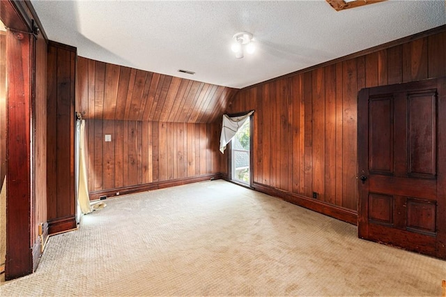 118 Spruce St, Leavenworth, KS 66048 - unfurnished room featuring wooden walls, light carpet, lofted ceiling, and a textured ceiling