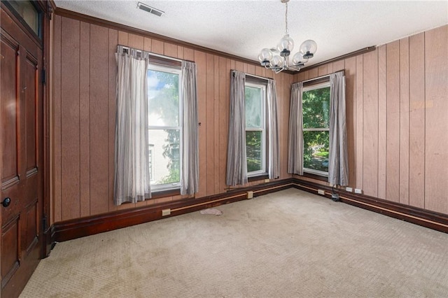 118 Spruce St, Leavenworth, KS 66048 - carpeted spare room featuring a chandelier, healthy amount of natural light, wooden walls, and a textured ceiling