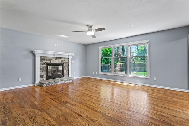 1321 SW Crossing Dr, Lees Summit, MO 64081 - unfurnished living room featuring wood finished floors, ceiling fan, and a stone fireplace