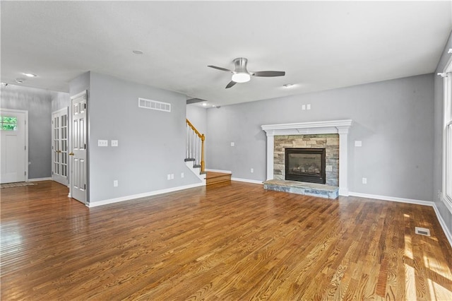 1321 SW Crossing Dr, Lees Summit, MO 64081 - unfurnished living room featuring a ceiling fan, wood finished floors, stairs, and a stone fireplace