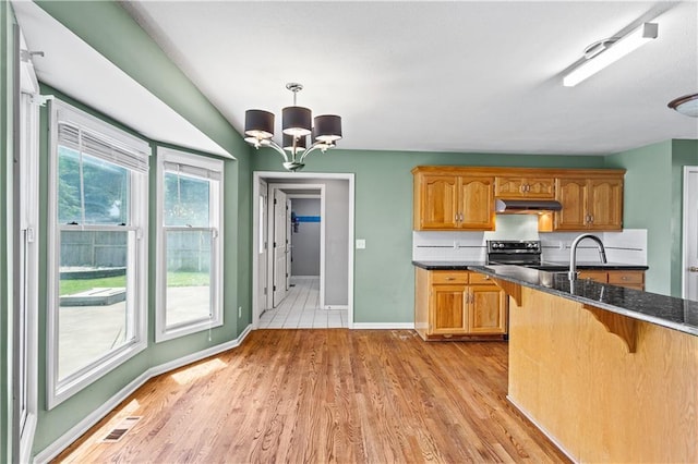 1321 SW Crossing Dr, Lees Summit, MO 64081 - kitchen featuring under cabinet range hood, stainless steel electric range oven, a chandelier, and light wood-style floors