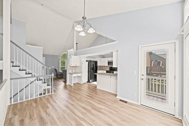 17277 W 157th St, Olathe, KS 66062 - unfurnished living room with a chandelier, stairway, high vaulted ceiling, and light wood-style flooring