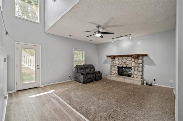 17277 W 157th St, Olathe, KS 66062 - unfurnished living room with a fireplace, rail lighting, a ceiling fan, a textured ceiling, and wood finished floors