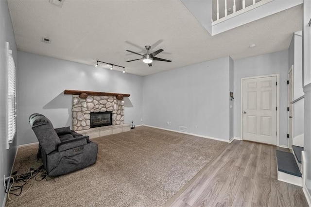 17277 W 157th St, Olathe, KS 66062 - unfurnished living room with ceiling fan, a stone fireplace, wood finished floors, rail lighting, and a textured ceiling