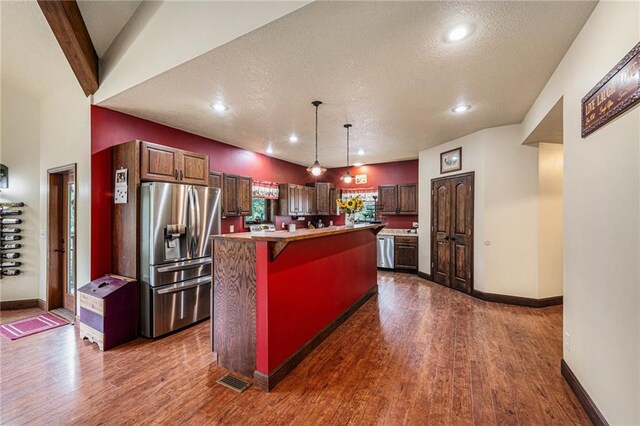 9750 SW 200th St, Smithville, MO 64089 - kitchen with stainless steel appliances, a kitchen island, dark wood finished floors, a textured ceiling, and a breakfast bar