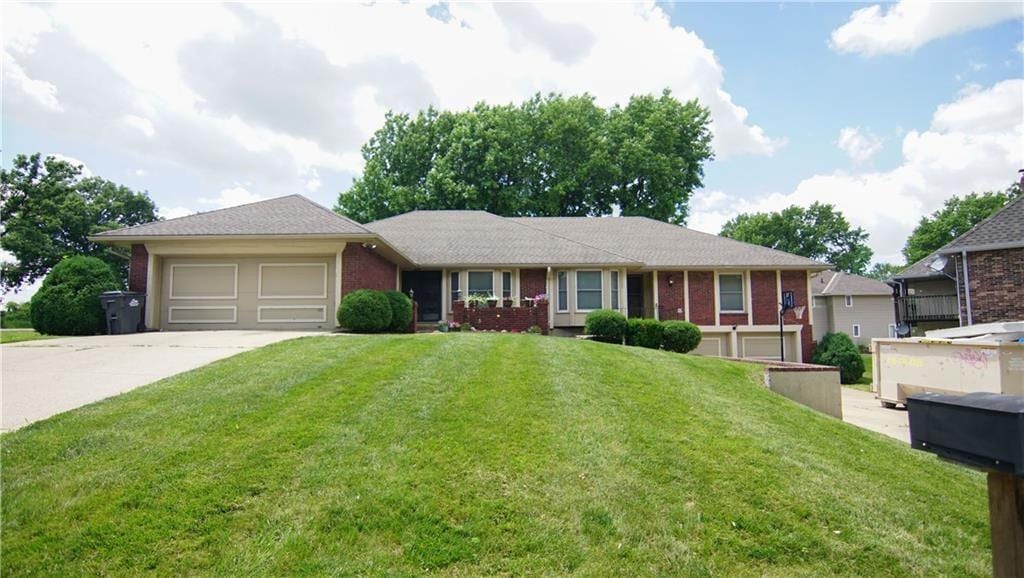 1101-1103 N 1st St, Blue Springs, MO 64014 - ranch-style home featuring concrete driveway, an attached garage, brick siding, and a front yard