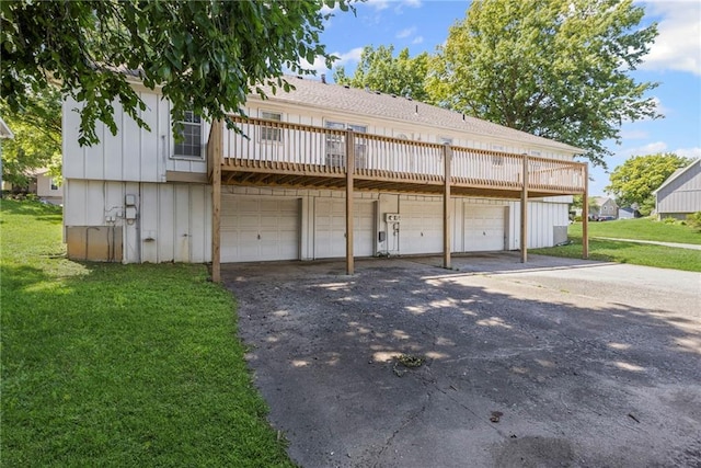 10131 W 84th St, Overland Park, KS 66212 - rear view of house featuring asphalt driveway, board and batten siding, a lawn, a wooden deck, and an attached garage