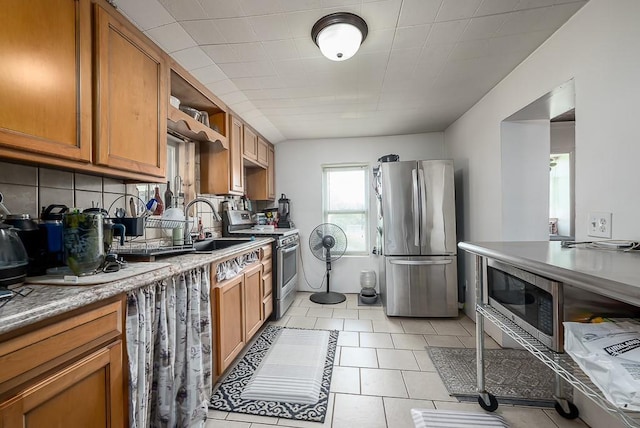 24305 Loring Rd, Lawrence, KS 66044 - kitchen with appliances with stainless steel finishes, brown cabinets, decorative backsplash, and light tile patterned flooring