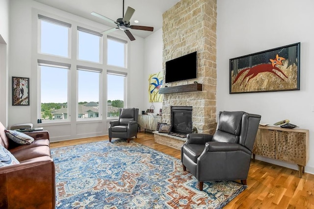 8319 Pickering St, Lenexa, KS 66227 - living area featuring a fireplace, a ceiling fan, a high ceiling, and wood finished floors