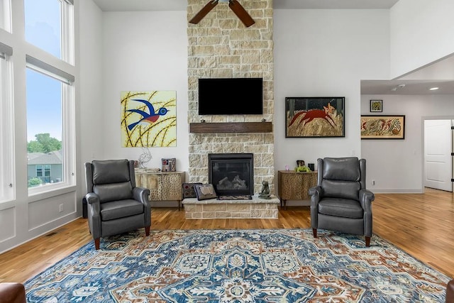 8319 Pickering St, Lenexa, KS 66227 - living room with a fireplace, a ceiling fan, a towering ceiling, and wood finished floors