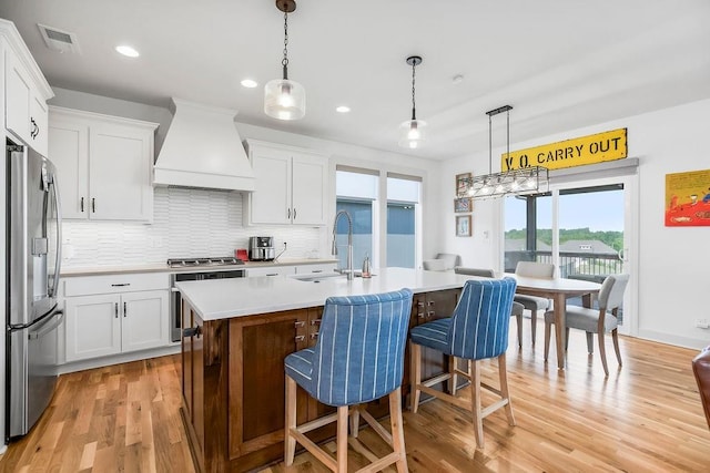 8319 Pickering St, Lenexa, KS 66227 - kitchen featuring custom exhaust hood, appliances with stainless steel finishes, light countertops, light wood finished floors, and tasteful backsplash