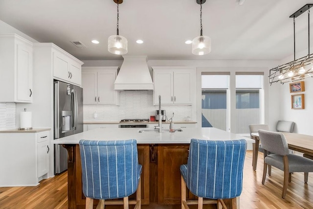 8319 Pickering St, Lenexa, KS 66227 - kitchen featuring custom range hood, stainless steel refrigerator with ice dispenser, light countertops, decorative backsplash, and light wood finished floors