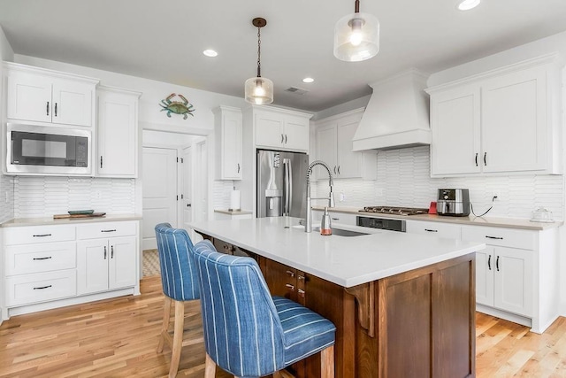 8319 Pickering St, Lenexa, KS 66227 - kitchen featuring stainless steel appliances, premium range hood, light wood-type flooring, decorative backsplash, and recessed lighting