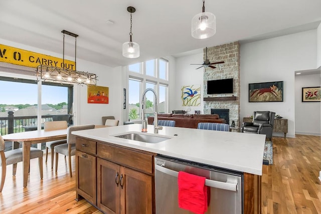 8319 Pickering St, Lenexa, KS 66227 - kitchen with stainless steel dishwasher, a fireplace, hanging light fixtures, a ceiling fan, and light wood-type flooring