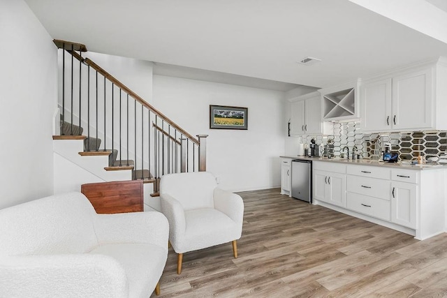 8319 Pickering St, Lenexa, KS 66227 - indoor wet bar with light wood-type flooring, stainless steel dishwasher, tasteful backsplash, and stairway