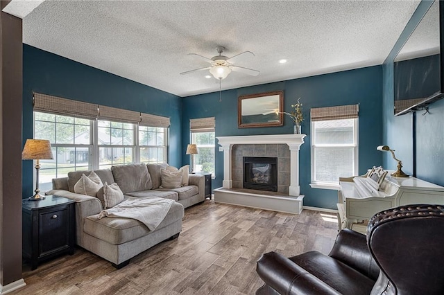 1210 NW Persimmon Dr, Grain Valley, MO 64029 - living area featuring ceiling fan, a textured ceiling, wood finished floors, a tiled fireplace, and recessed lighting