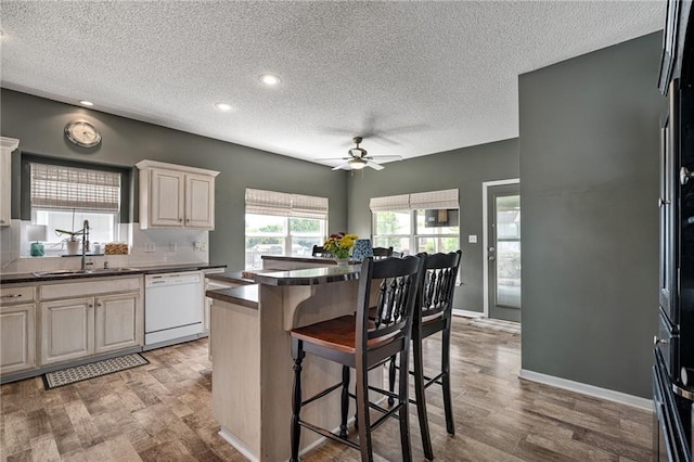 1210 NW Persimmon Dr, Grain Valley, MO 64029 - kitchen featuring dishwasher, a textured ceiling, a ceiling fan, a kitchen bar, and dark countertops