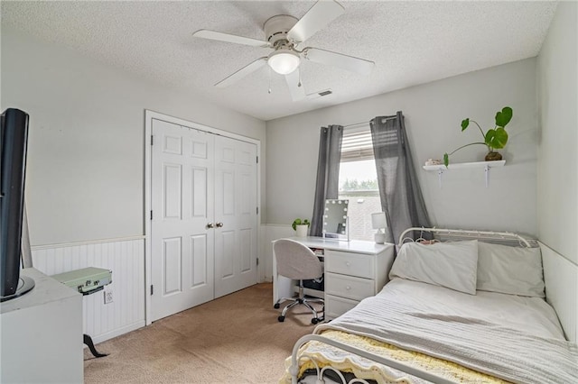 1210 NW Persimmon Dr, Grain Valley, MO 64029 - bedroom featuring light carpet, a textured ceiling, a closet, ceiling fan, and a wainscoted wall