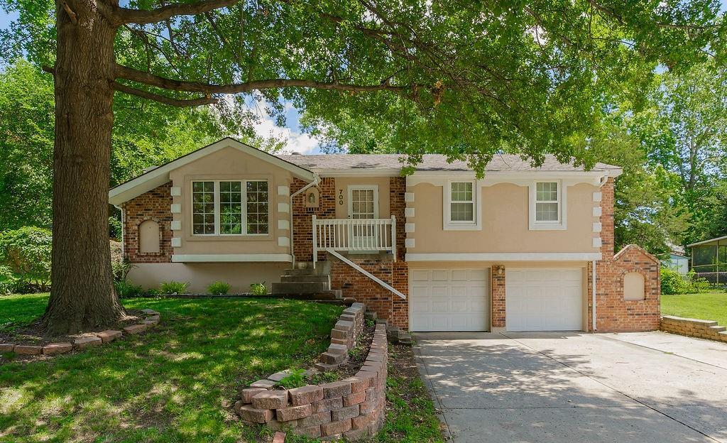 700 NW Canterbury Rd, Blue Springs, MO 64015 - ranch-style home featuring an attached garage, concrete driveway, brick siding, stucco siding, and a front lawn