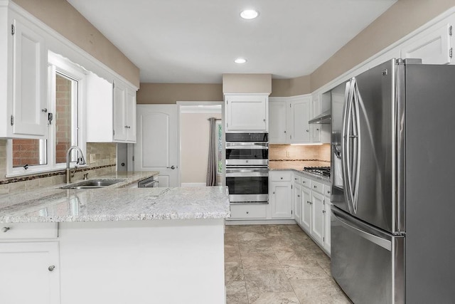 7718 W 100th St, Overland Park, KS 66212 - kitchen with appliances with stainless steel finishes, a peninsula, light stone counters, white cabinetry, and backsplash