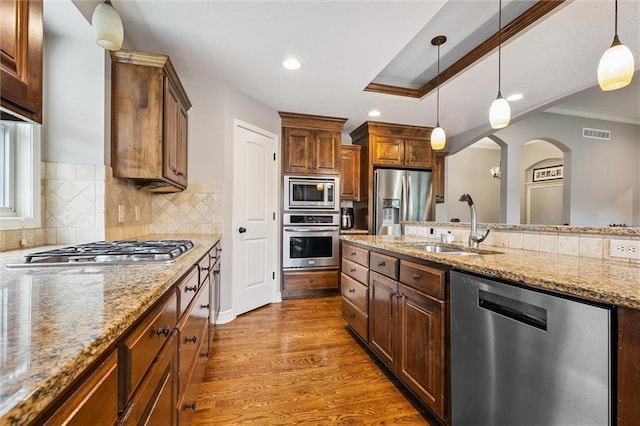 18501 S Butternut St W, Gardner, KS 66030 - kitchen featuring appliances with stainless steel finishes, ornamental molding, hanging light fixtures, dark wood-type flooring, and tasteful backsplash