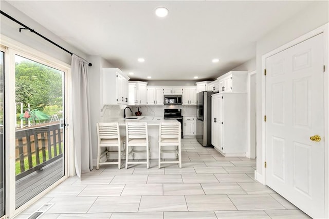 14733 Hickory Dr, Bonner Springs, KS 66012 - kitchen featuring appliances with stainless steel finishes, a peninsula, light countertops, recessed lighting, and white cabinetry