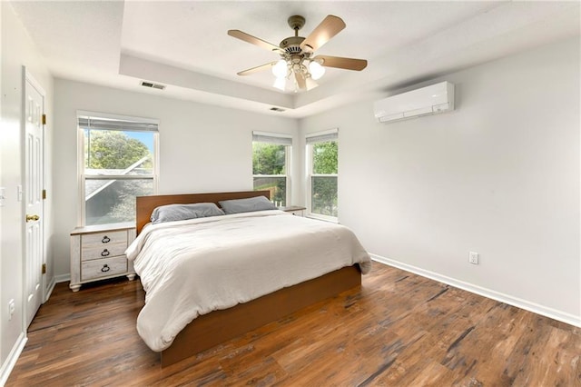 14733 Hickory Dr, Bonner Springs, KS 66012 - bedroom featuring a tray ceiling, an AC wall unit, wood finished floors, and a ceiling fan