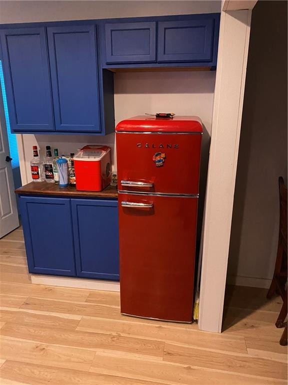 1807 Dodds Camp Rd, Climax Springs, MO 65324 - kitchen featuring refrigerator, blue cabinets, light wood finished floors, and dark countertops