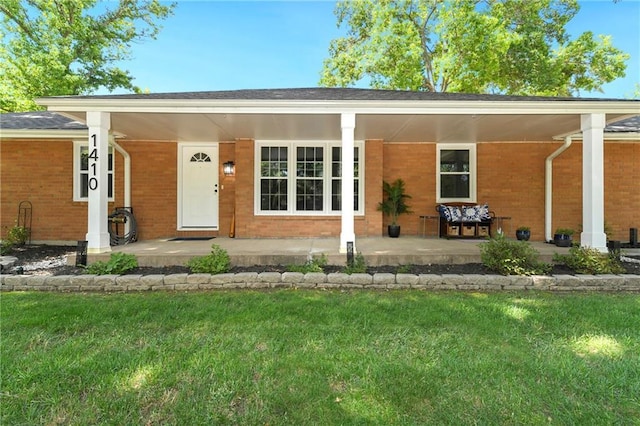 1410 Vilas St, Leavenworth, KS 66048 - view of exterior entry featuring brick siding, a yard, and a porch