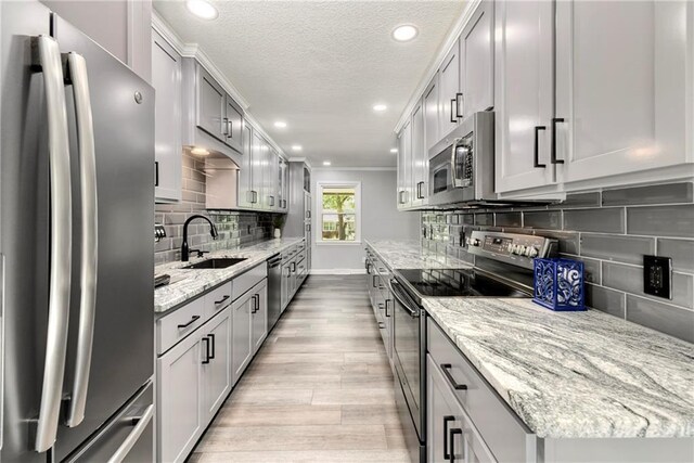 1410 Vilas St, Leavenworth, KS 66048 - kitchen with appliances with stainless steel finishes, light wood-style flooring, decorative backsplash, light stone countertops, and a textured ceiling