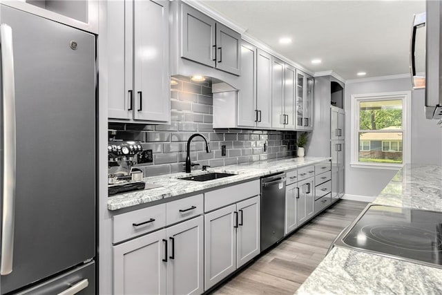 1410 Vilas St, Leavenworth, KS 66048 - kitchen featuring stainless steel appliances, crown molding, decorative backsplash, light wood finished floors, and glass insert cabinets