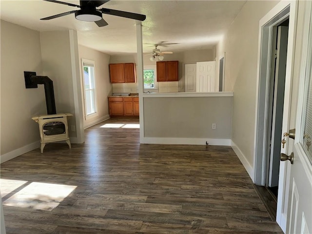 310 E 3rd Ave, Garnett, KS 66032 - kitchen with a wood stove, brown cabinets, ceiling fan, dark wood-style floors, and a peninsula
