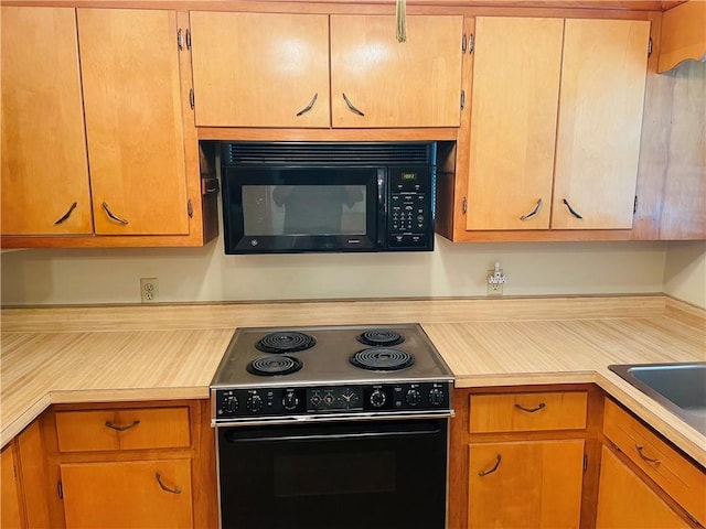 506 1st Ter, Lansing, KS 66043 - kitchen featuring range with electric cooktop, black microwave, and light countertops
