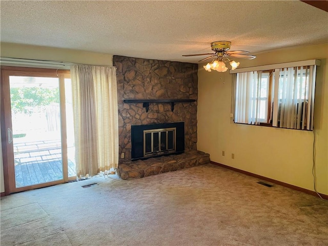 506 1st Ter, Lansing, KS 66043 - unfurnished living room featuring carpet, a textured ceiling, a stone fireplace, and ceiling fan