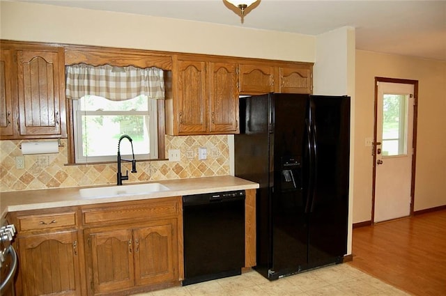 407 Hithergreen Dr, Lansing, KS 66043 - kitchen with black appliances, brown cabinetry, light countertops, decorative backsplash, and plenty of natural light