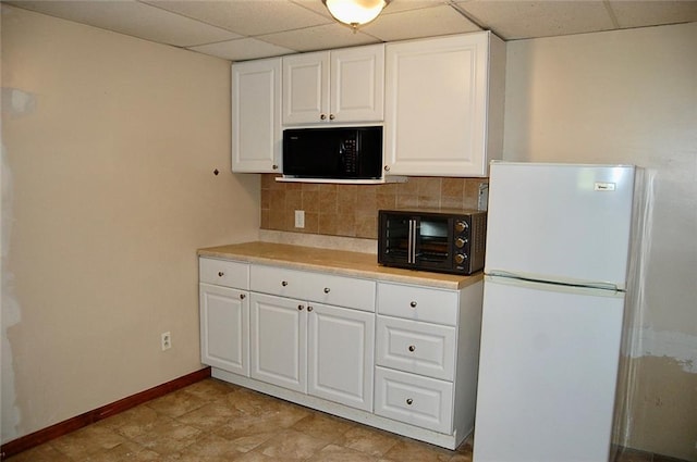407 Hithergreen Dr, Lansing, KS 66043 - kitchen with freestanding refrigerator, black microwave, a paneled ceiling, backsplash, and white cabinetry