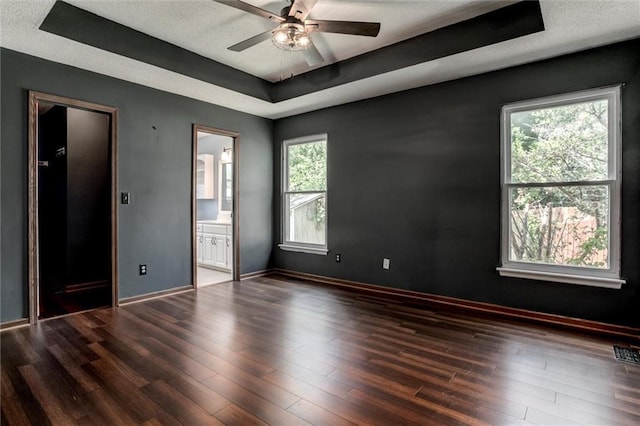 1039 Woodson Cir, Gardner, KS 66030 - spare room with a raised ceiling, healthy amount of natural light, a ceiling fan, and dark wood-style flooring