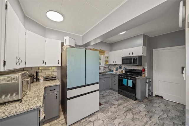 1340 Spruce St, Leavenworth, KS 66048 - kitchen with stainless steel microwave, freestanding refrigerator, black range with gas cooktop, and tasteful backsplash